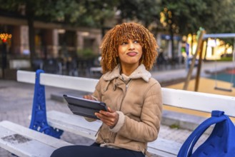 Creative beauty young latin woman sitting on a bench using digital tablet to work in the city