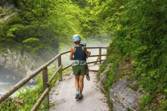 Mother carrying her child while hiking on a misty summer day in vintgar gorge near bled, slovenia,