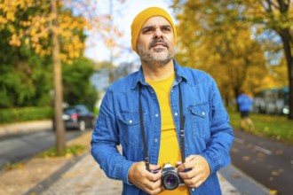Frontal portrait of a male mature tourist gazing the city while holding digital camera