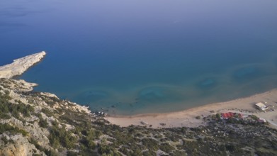 Aerial view of a secluded beach with clear blue water and rocky surroundings, Tsambika Beach,