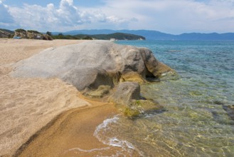 Rocky beach with clear sea water and gentle waves, surrounded by nature, beach, rocks in the shape