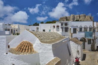 Castle on a hill above a town with traditional white houses, sunny streets and clear skies, St