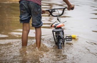 Children wade through a flooded street after heavy rains in Guwahati, India on April 28, 2025