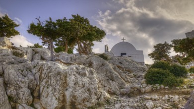 HDR, Small chapel on rocky terrain with trees and cloudy sky in the background, Chapel of Agios