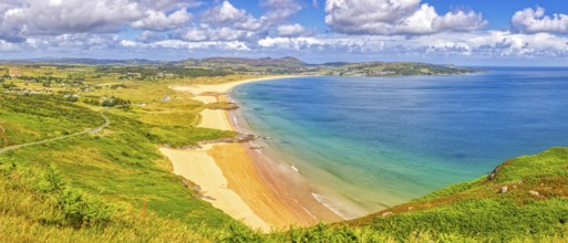 Extensive coastal landscape with golden sandy beaches and blue sea under a cloudy sky,