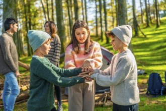 Three caucasian young brothers and sister playing enjoying camping in the forest with their parents