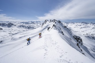 Two ski tourers in mountain landscape with snow, mountain panorama with summit of the Grisons Alps,