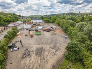 Landscape view of a large construction site in the countryside, surrounded by houses and a cloudy