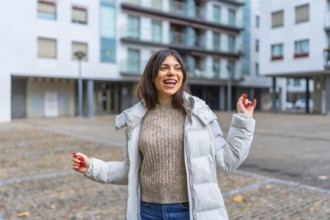 Happy beauty woman with jacket and warm clothes dancing in the city