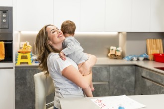 Mom lovingly embraces her baby in a modern kitchen, creating a heartwarming moment of family