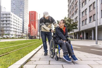 Caregiver assisting a young man with disability, strolling through a city environment, promoting