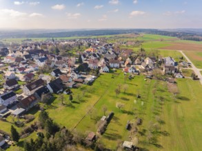 Wide green spaces and scattered houses in a village that stretches through a peaceful landscape