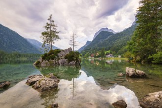 Hintersee with rocks and trees in the foreground, surrounded by mountains after sunset with