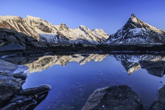 Evening light over steep mountains, reflection in fjord, winter, Moskenesoya, Lofoten, Norway,