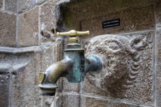 Old metal water tap on a weathered stone wall, Le Mont-Saint-Michel
