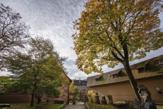 Cemetery with autumn tree at St. Nicholas and St. Ulrich Church, Kirchenberg 15,