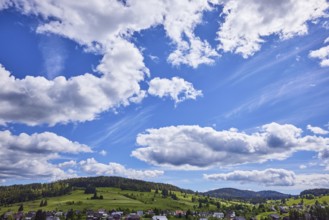 Blue sky with cumulus clouds and hills of the Black Forest with meadows and forest as seen from the