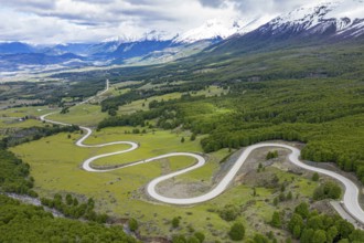 Road Carretera Austral winding down into the valley of Villa Cerro Castillo, snowcapped mountains