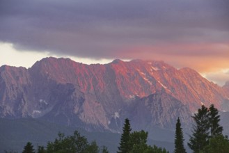 Mountain peak in bright red at sunset with dramatic clouds in the sky, Wallgau, Bavaria, Germany,
