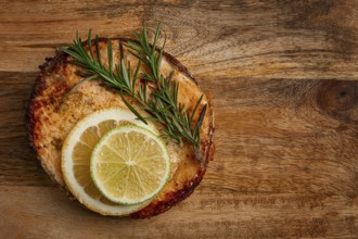 Salmon steak, fried, on a cutting board, top view, rosemary, lemon and lime, homemade, one serving,