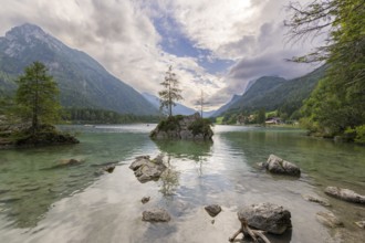 Hintersee with rocks and trees in the foreground, surrounded by mountains after sunset with