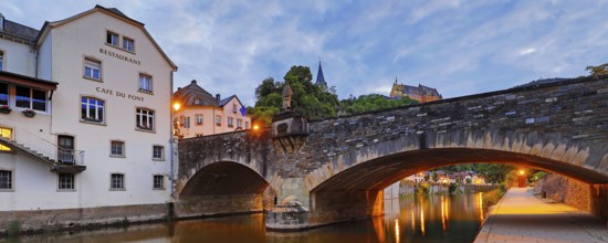Town view of Vianden with the old stone bridge over the river Our and the castle in the evening,