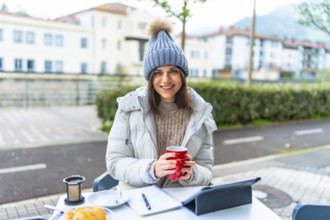 Beauty female caucasian entrepreneur working with digital tablet sitting in an outdoor cafeteria