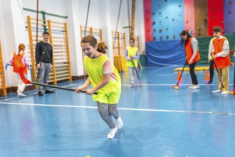 Elementary school children playing floorball in gym class, learning teamwork and sportsmanship