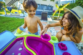 Mother and son enjoying quality time together, playing with a colorful water table in their
