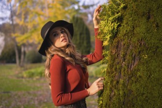Lifestyle, portrait of a caucasian girl in a black hat at sunset in a green park