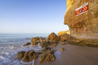 ROCKFALL UNSTABLE CLIFFS, KEEP A SAFE DISTANCE is written in English on a warning sign in Portugal