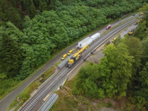 Aerial view of a railway line with longer track, vehicles and construction site workers, surrounded