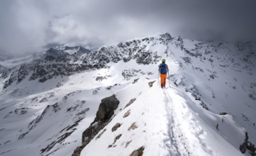 Mountaineer descending the narrow ridge of Piz Laviner, view of mountain panorama in wintry