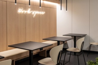Empty tables and chairs illuminated by modern light fixtures create a workspace in an airport