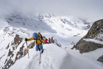 Mountaineers climbing the ridge of Piz Laviner, view of wintry mountain landscape, Grisons Haute