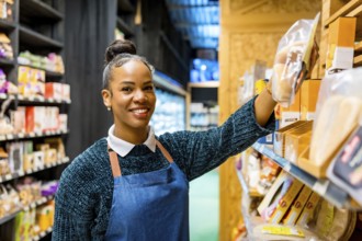 Friendly saleswoman arranging gluten free products on shelves, working in an organic supermarket,