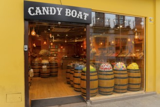 Confectionery shop with wooden barrels full of sweets and a yellow façade presenting a tempting