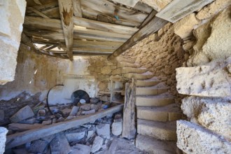 The interior of an old, abandoned mill with stone staircase and decaying wooden beams, windmill,