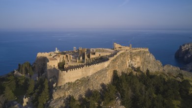 Drone shot, Acropolis of Lindos, Late afternoon light, Historic castle on a cliff above the sea in