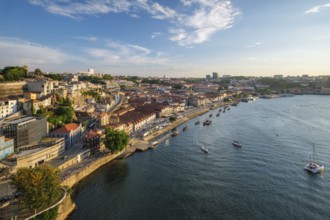View of Vila Nova de Gaia city and Douro river with tourist boats on sunset. Porto, Portugal,