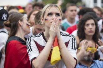 A woman watches the football match in the fan zone at the Brandenburg Tor during the quarter-final