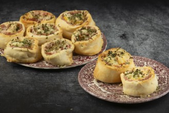 Freshly baked sausage and cheese snails on decorative plates