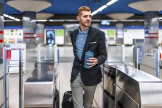 Young professional walking through subway turnstile holding reusable coffee cup, commuting to work