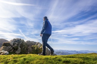 Male hiker using a walking stick while enjoying a sunny day on the summit of mount penas de aya or