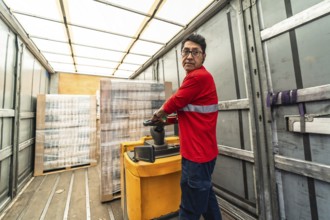 Rear view of a concentrated latin man worker loading a delivery truck in distribution warehouse