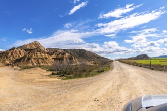 Scenic view of a dirt road winding through the geological formations of bardenas reales desert in