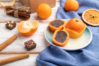 Truffle chocolate tangerine candies on a white wooden background and blue linen textile. Side view,