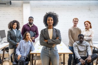 Confident african woman standing with arms crossed next to colleagues in a coworking