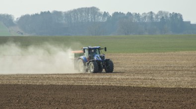 Spring farming, spreading fertilizer with tractor on field in Ystad municipality, Skåne county,