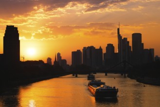 The sun sets behind the Frankfurt bank skyline while a ship sails along the Main, Frankfurt am